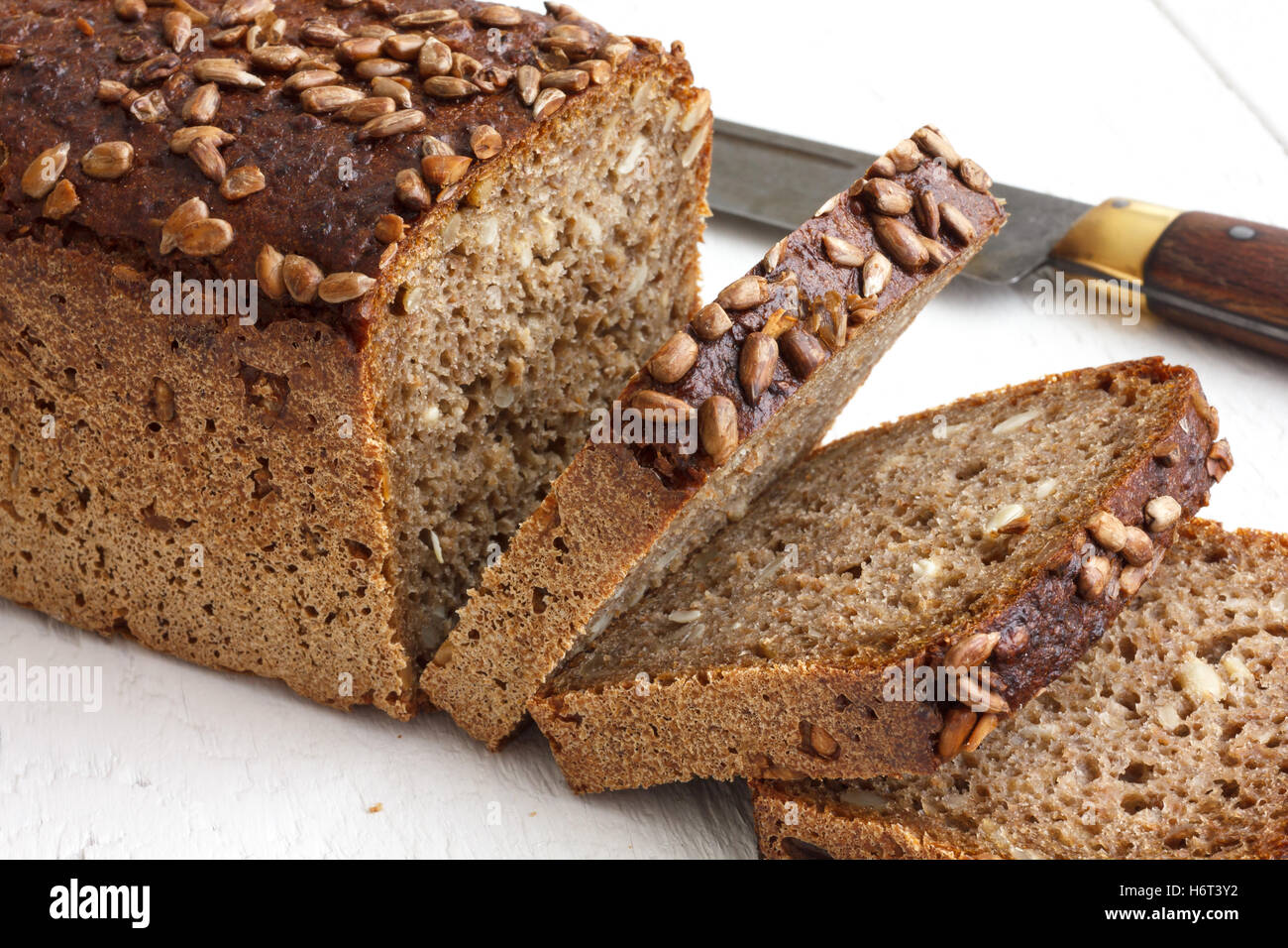 Square di semi di girasole a fette di pane rustico superficie bianca. Foto Stock