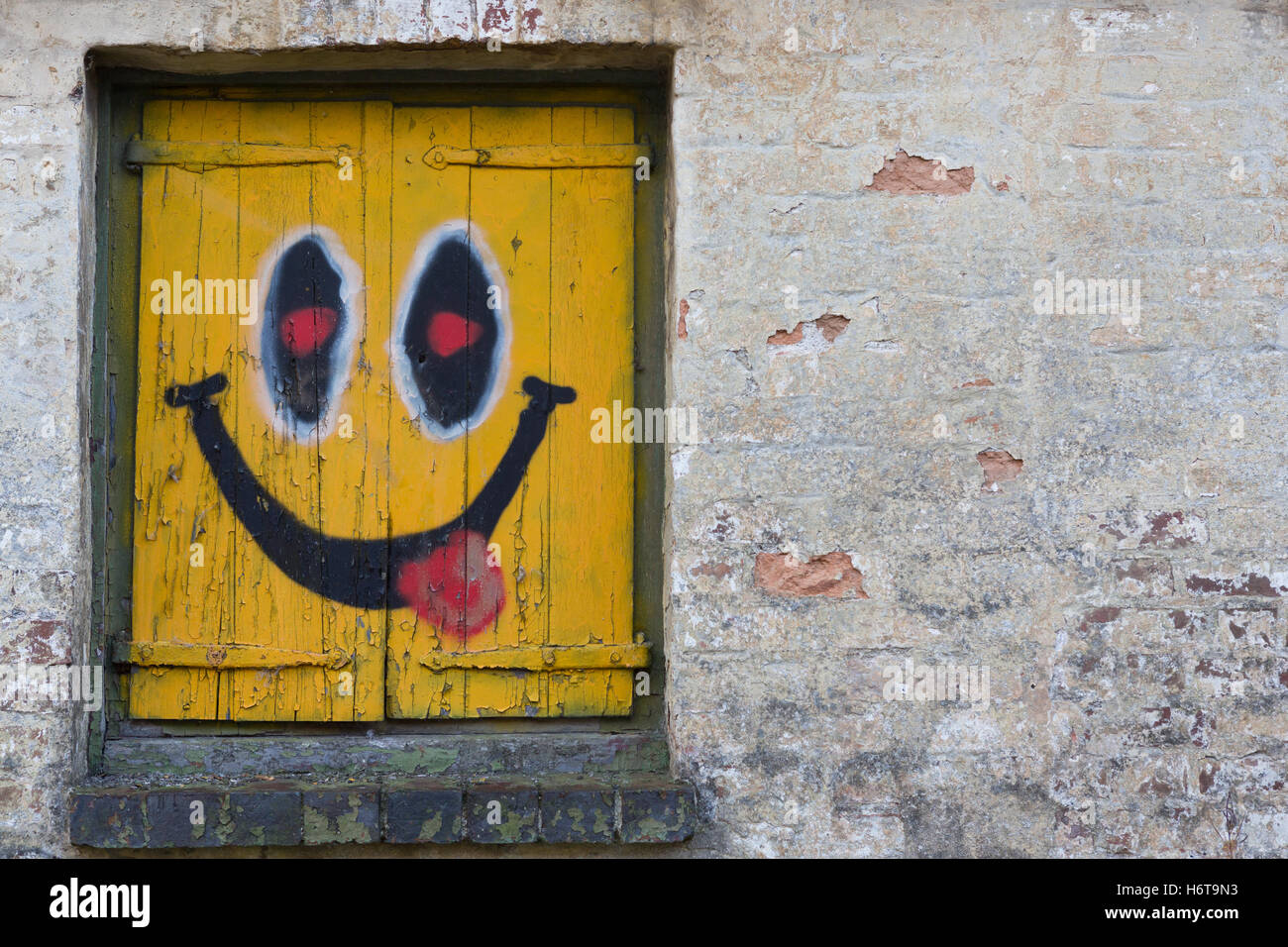 Un sorriso, felice volto dipinto sul lato di un edificio abbandonato Foto Stock