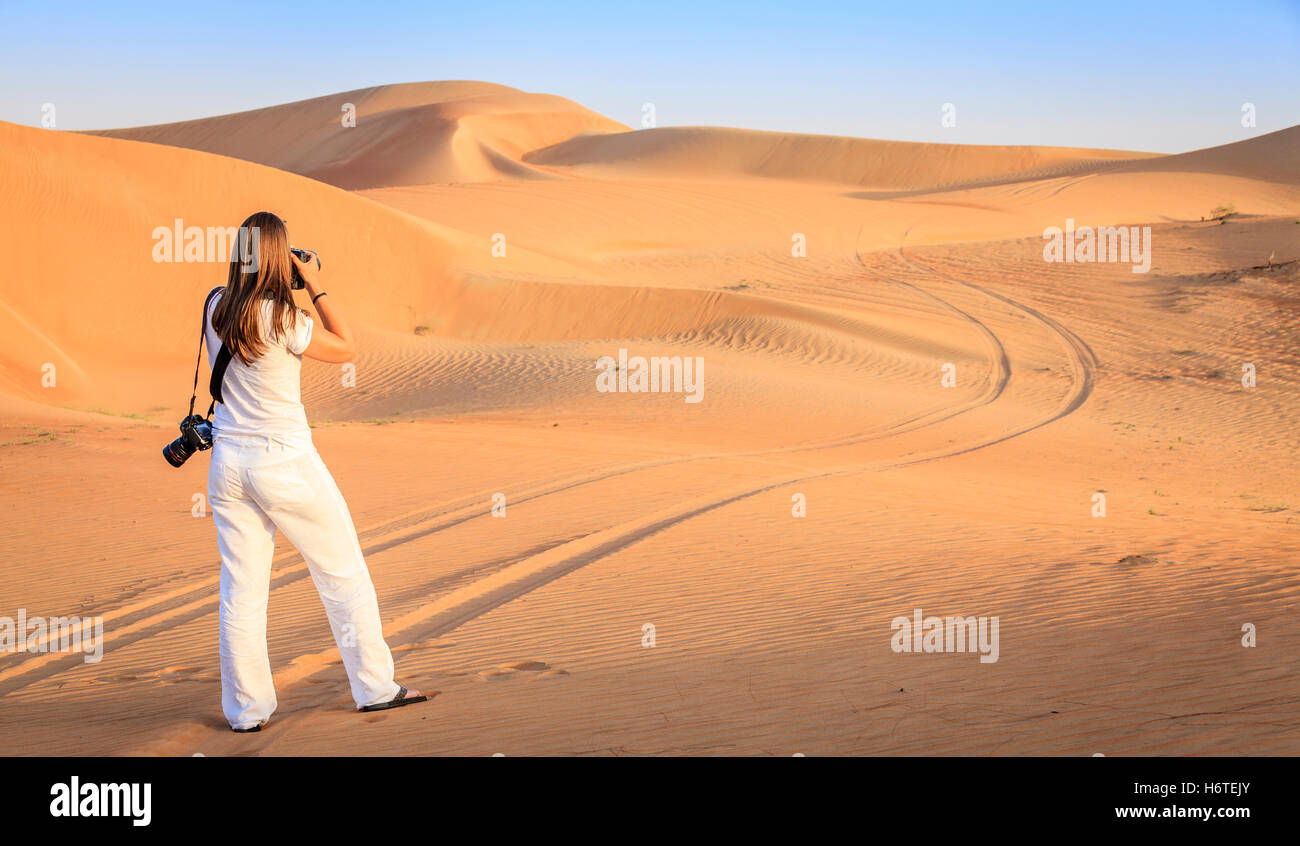 Una donna è di scattare le foto di dune nel deserto area di conservazione vicino a Dubai, Emirati arabi uniti Foto Stock