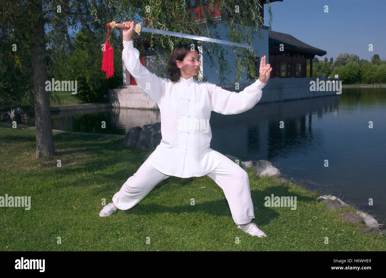 Donna, inizio 40s, facendo Tai Chi con la spada in un giardino cinese a Berlino Foto Stock
