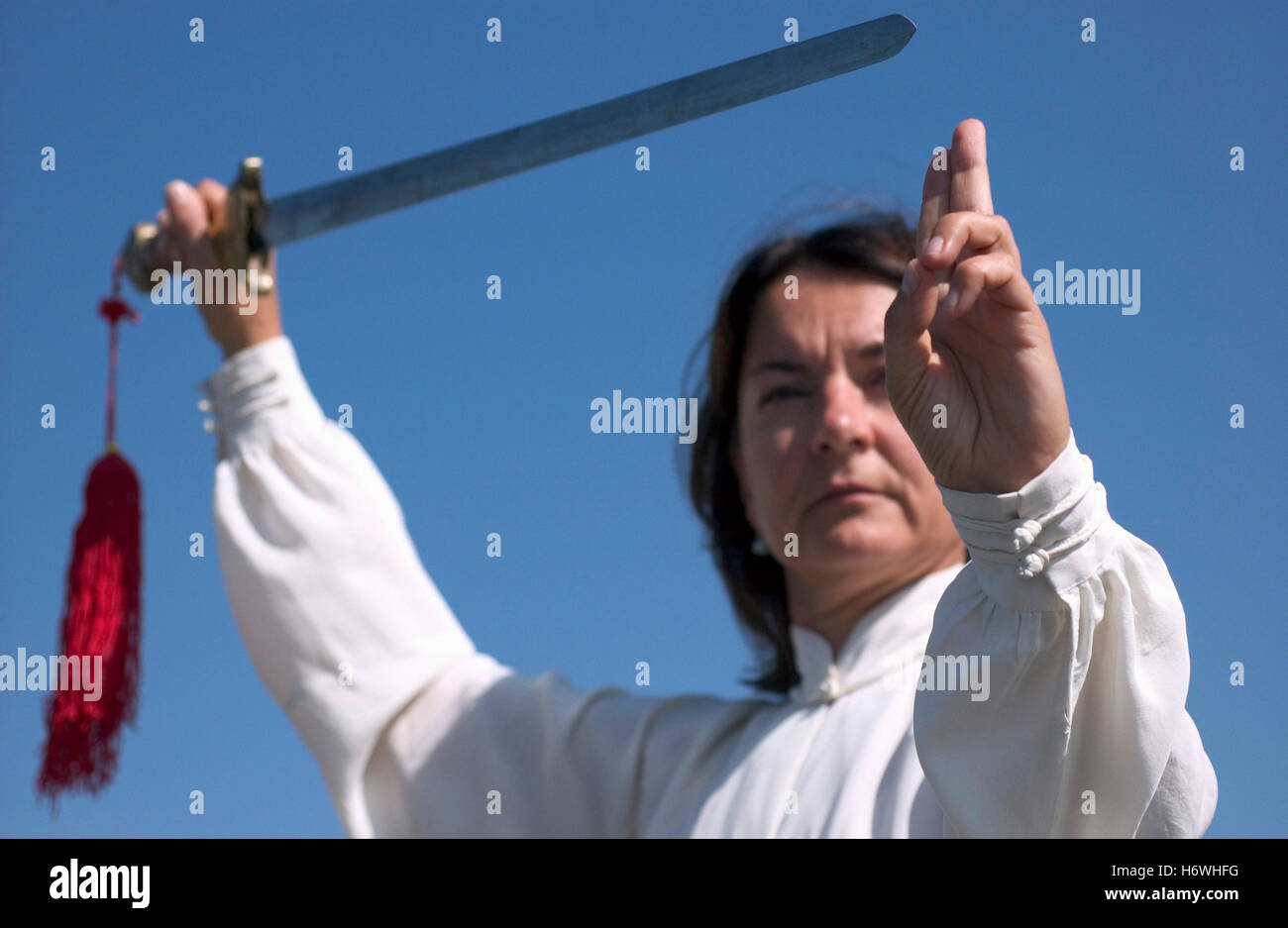 Donna, inizio 40s, facendo Tai Chi con la spada Foto Stock