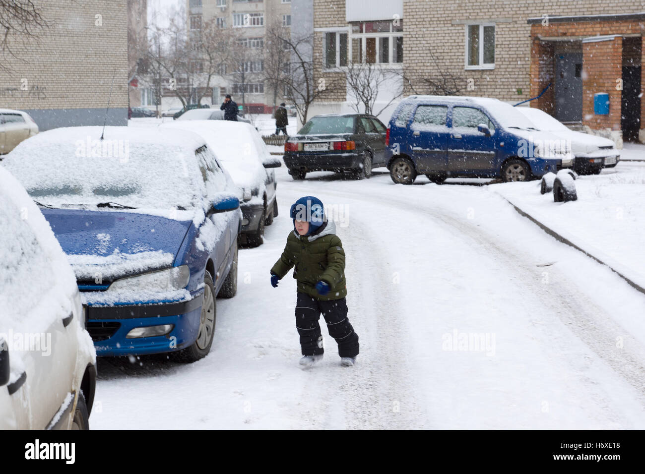 Inverno caldo vestito ragazzo giocando su una strada innevata Foto Stock