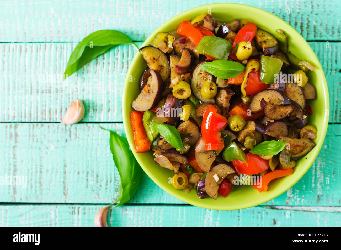 Piccante stufato di melanzane, peperoni, olive e capperi con le foglie di basilico. Vista superiore Foto Stock