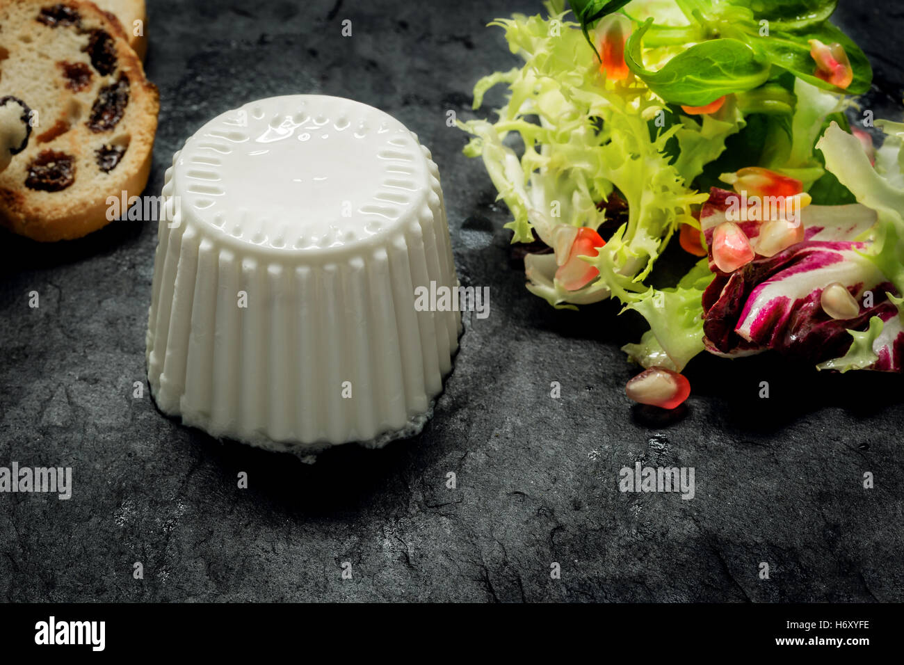 Close up di formaggio fresco con insalata di verdure fresche e melograno su scura pietra ardesia Foto Stock