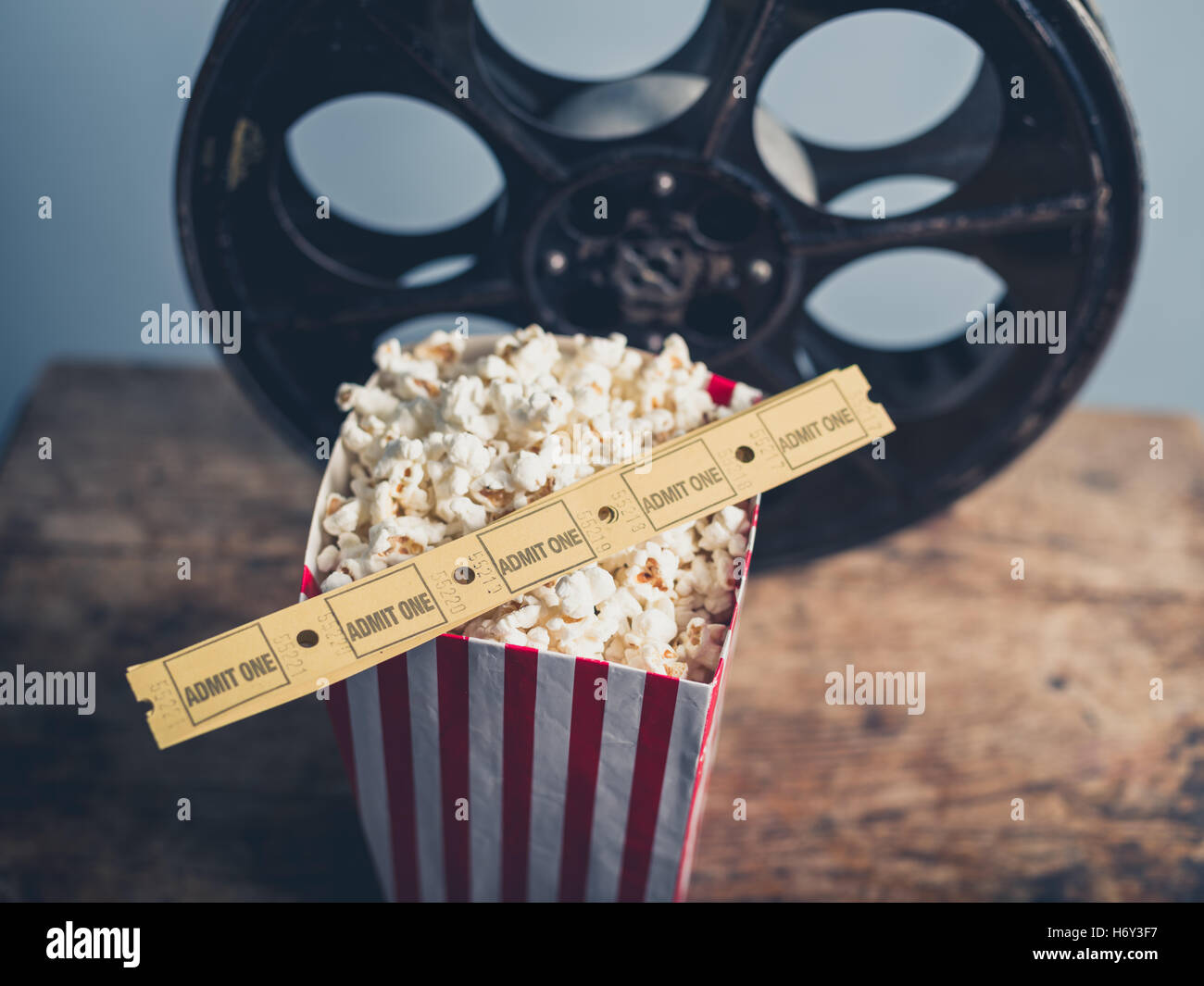 Concetto di cinema della vecchia bobina di pellicola con popcorn e biglietti per il cinema su una superficie in legno Foto Stock