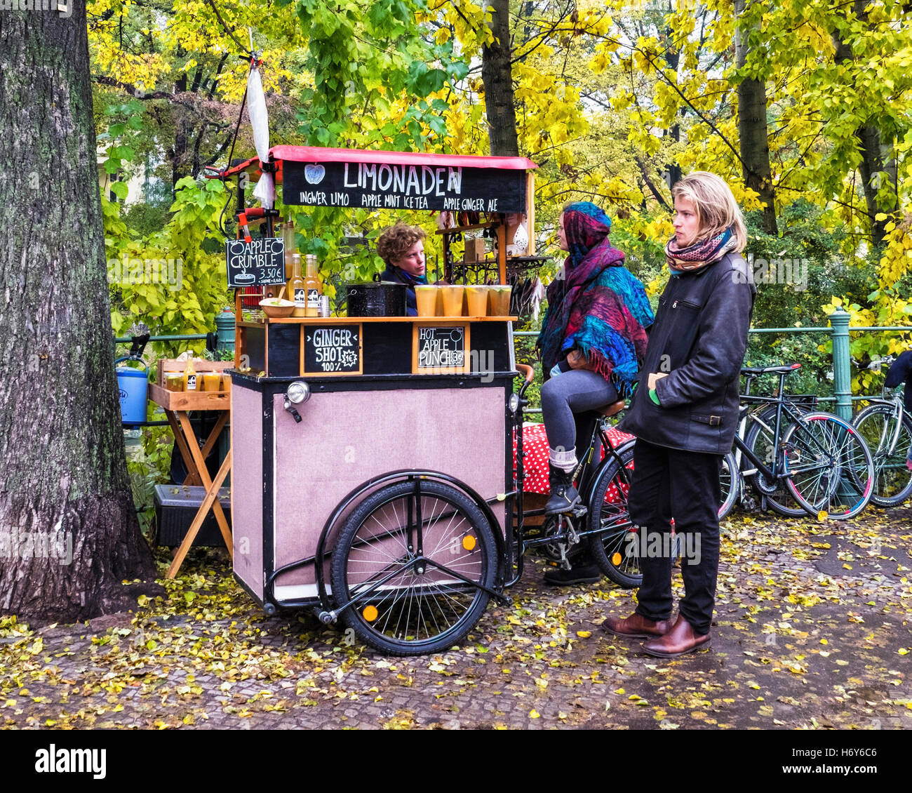 Mercato turco bancarelle che vendono cibi caldi e bevande fredde sotto giallo autunnale di alberi in autunno, Kreuzberg di Berlino Foto Stock