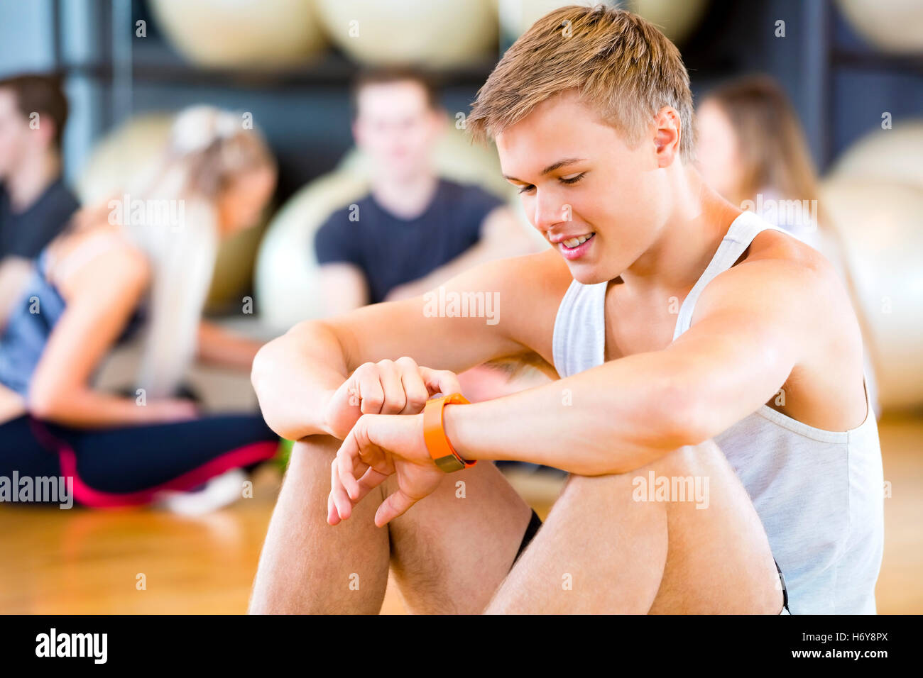 Uomo che utilizza Smart a guardare mentre gli amici seduti in palestra Foto Stock