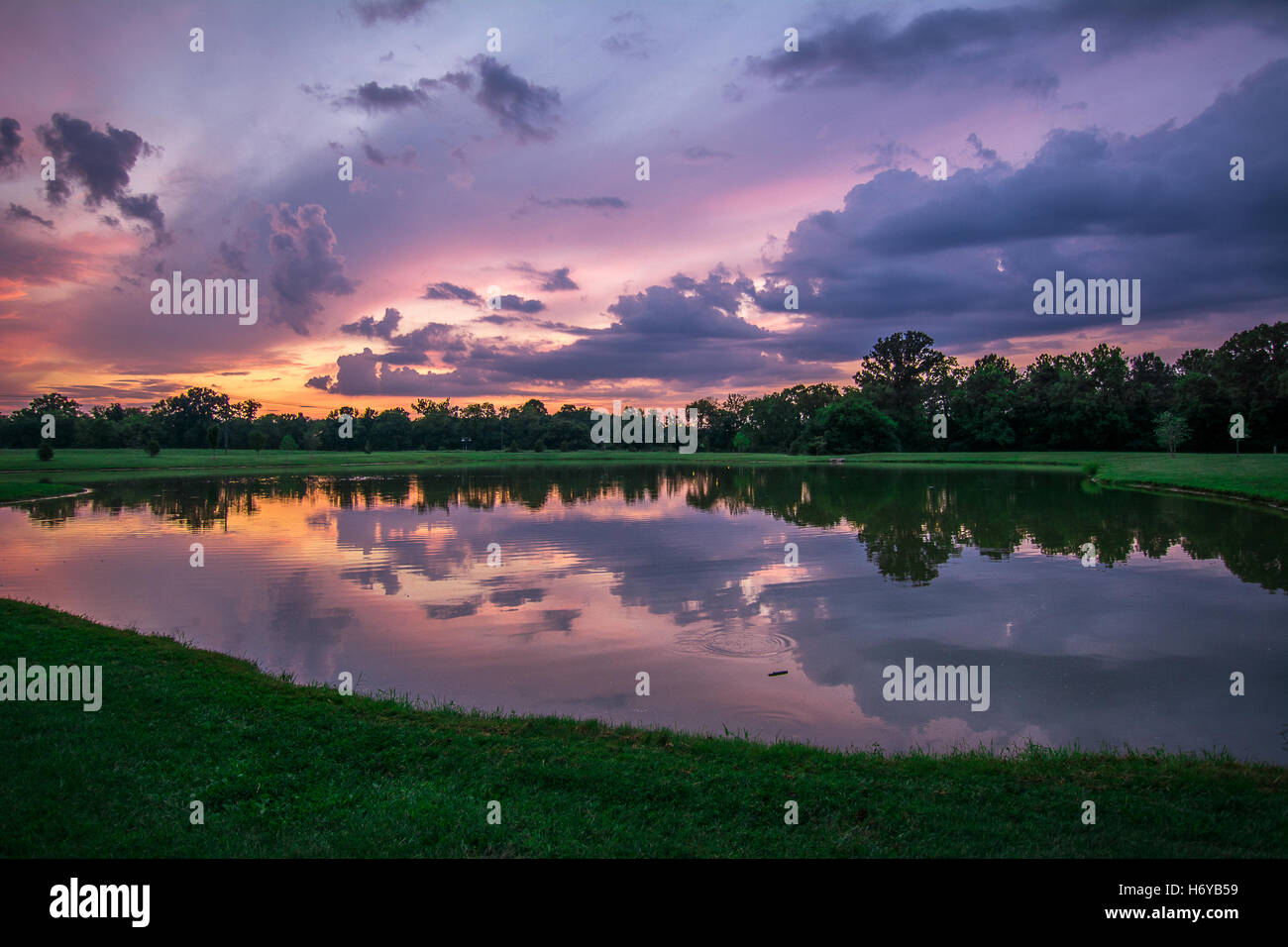 Tramonto crea un cielo viola e di riflessione in un lago Foto Stock