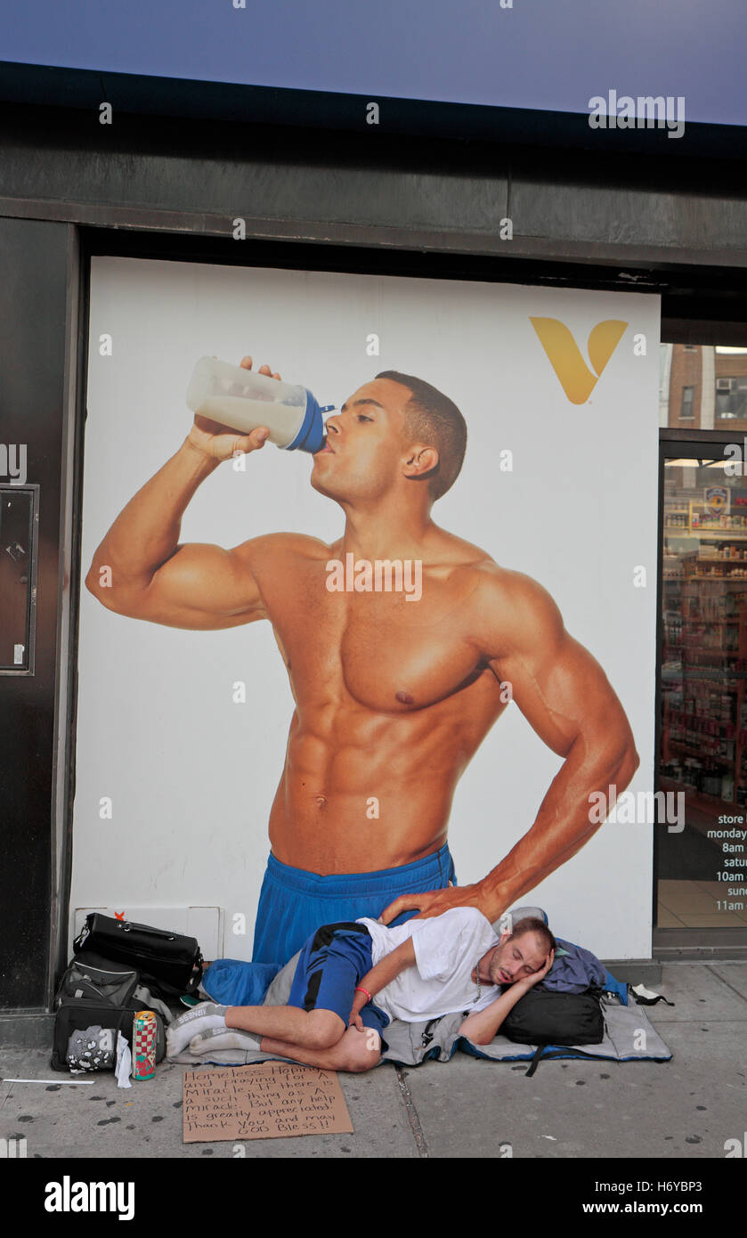 Senzatetto bianco uomo dorme sotto la foto di un montare l'uomo bianco al di fuori del VitaminShoppe, Manhattan, New York, Stati Uniti. Foto Stock