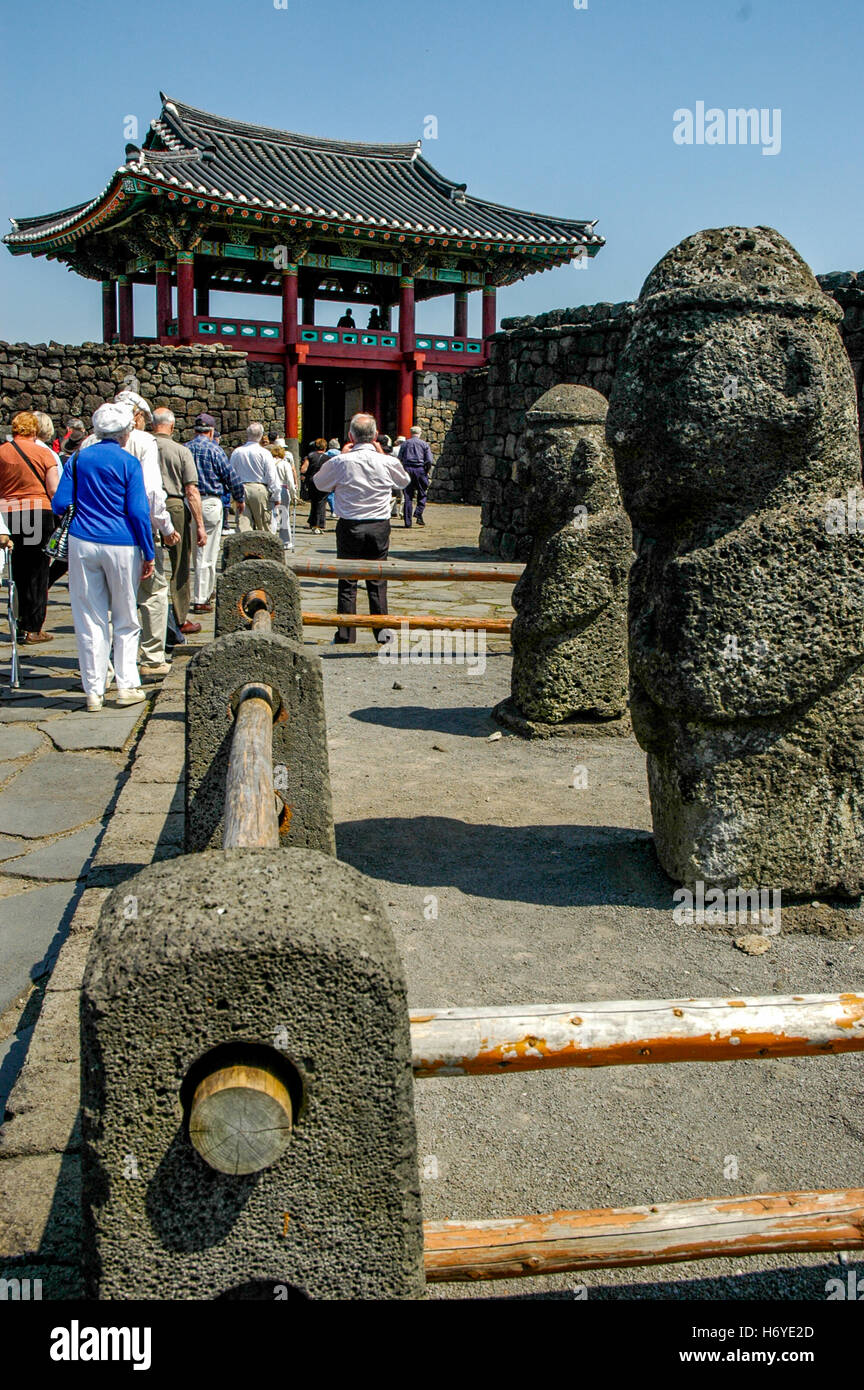 Visitatori e sculture in pietra al cancello di ingresso di seongeup folk village. jeju (cheju). sth COREA Foto Stock