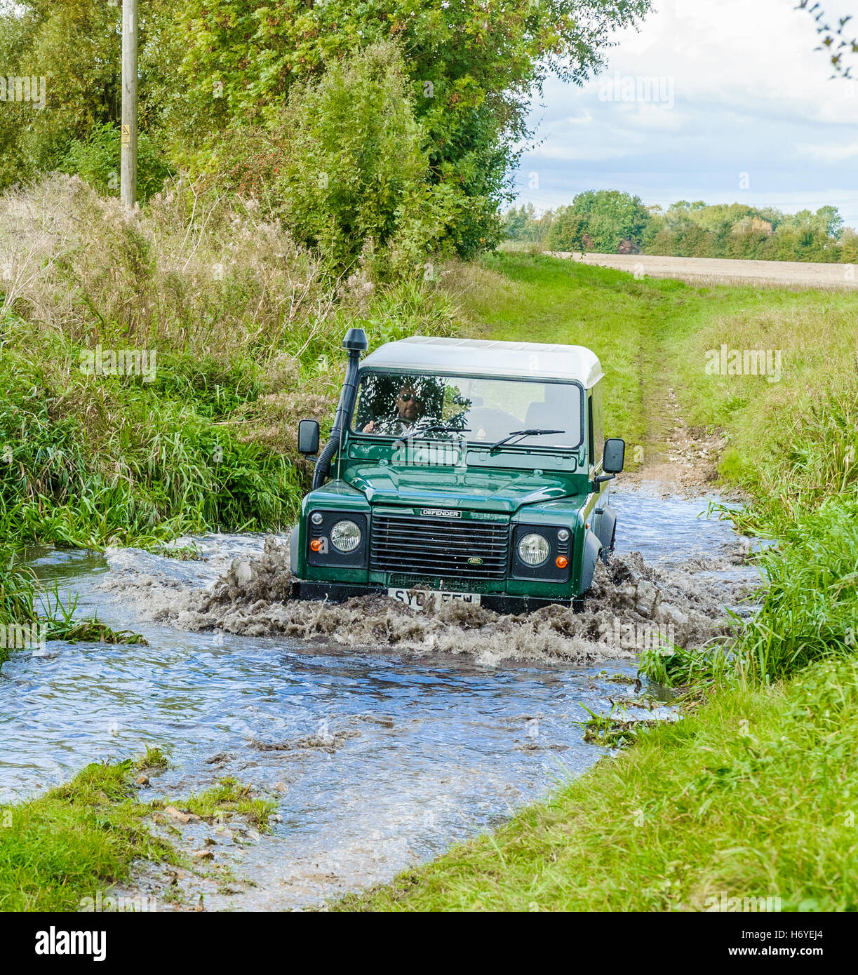 Un Landrover Defender 90 attraversamento o Guadato un ruscello o fiume Foto Stock