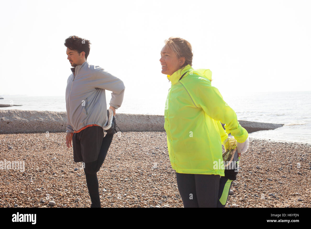 L uomo e la donna la formazione, in piedi su una gamba sola sulla spiaggia di Brighton Foto Stock