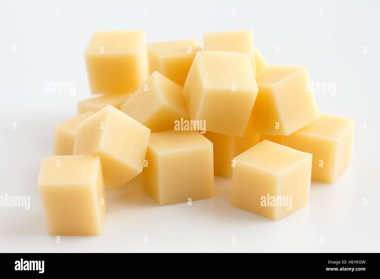 Cubetti di formaggio giallo impilati in maniera casuale sul bianco. Foto Stock