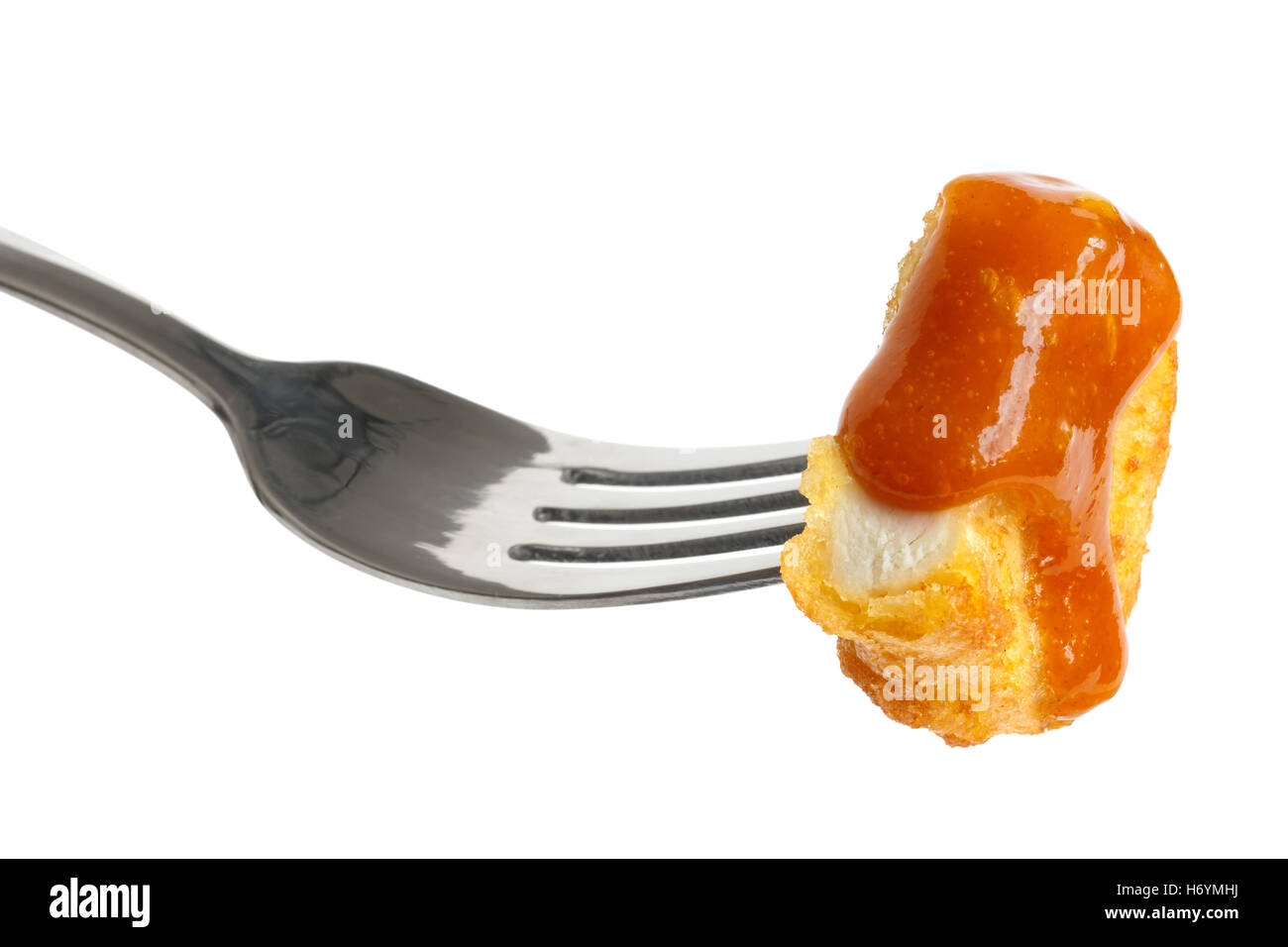 Singolo golden fritte martoriata pepita di pollo con salsa al curry su una forcella isolato su bianco. Il taglio di carne che mostra di texture. Foto Stock