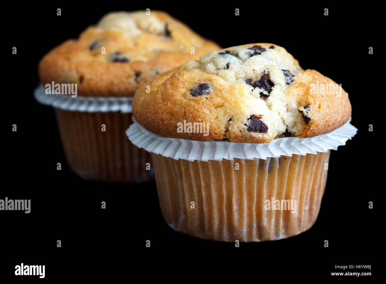 Due leggeri chocolate chip muffin nella camicia di cera sul nero. Foto Stock