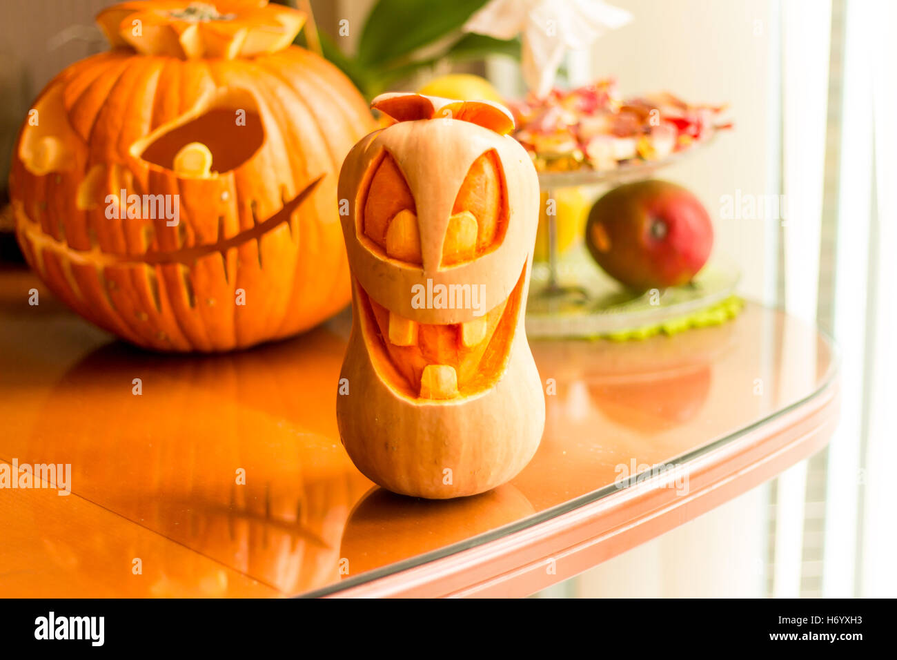 Sorridente arancione zucca di Halloween di testa su una tabella con un background di zucca e caramelle rack. Foto Stock