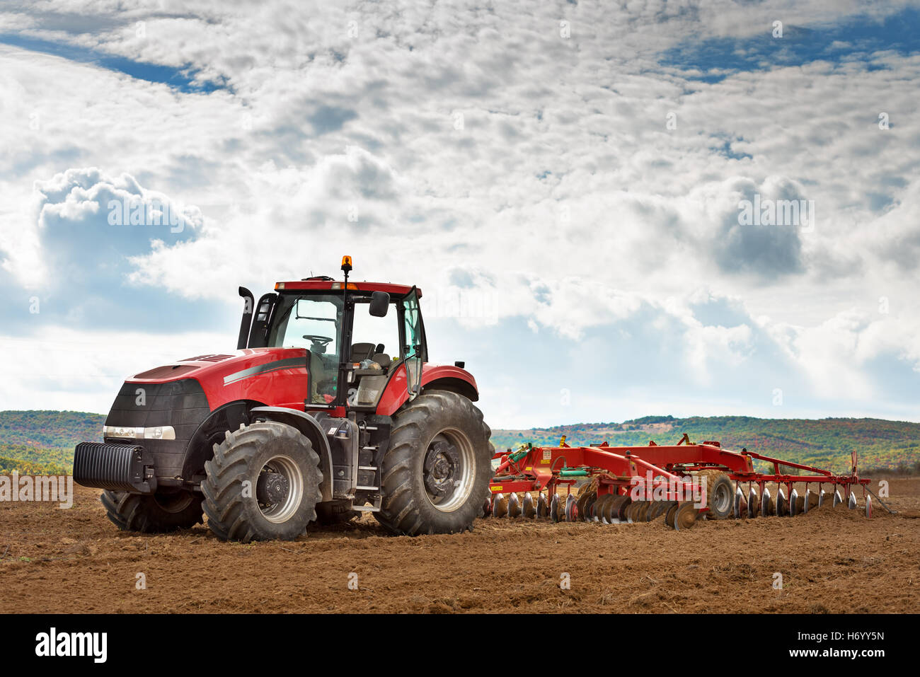 Moderno trattore rosso in campo agricolo. Foto Stock