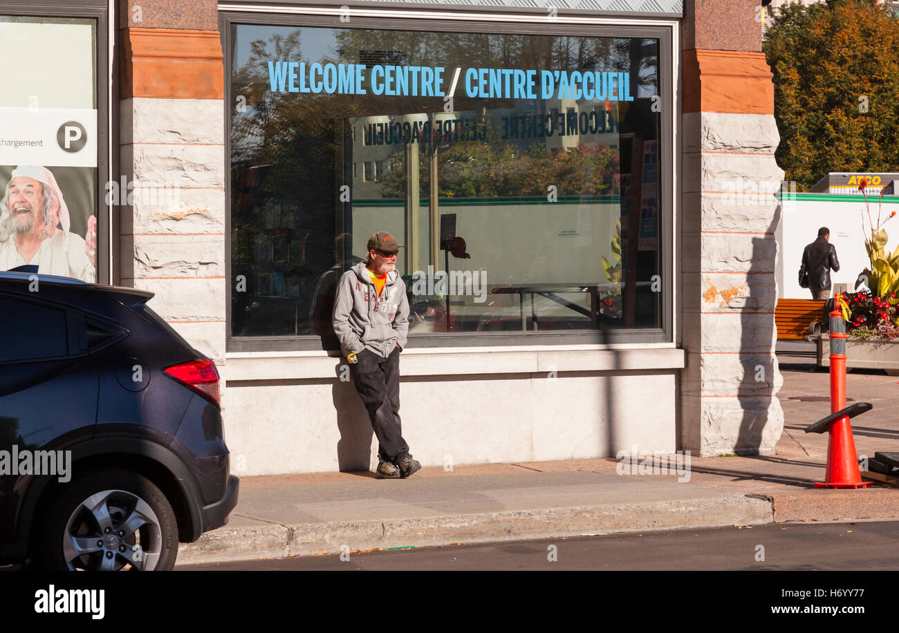 Un uomo appoggiato contro la finestra del centro di accoglienza in Ottawa, Ontario, Canada. Foto Stock