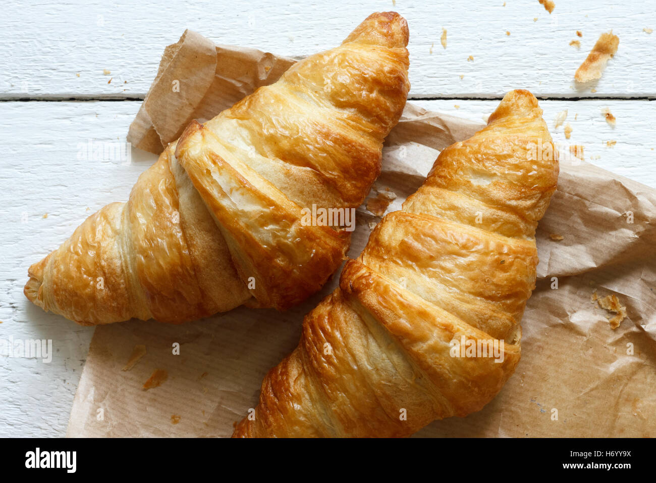 I croissant sulla borsa marrone sul rustico in legno bianco dal di sopra. Foto Stock