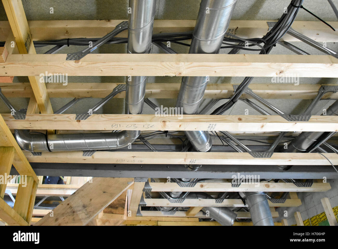 Interno del nuovo Regno Unito efficienza energetica casa passiva che mostra la costruzione di materiali & trunking di ventilazione installato all'interno del reticolo di travi a soffitto Foto Stock