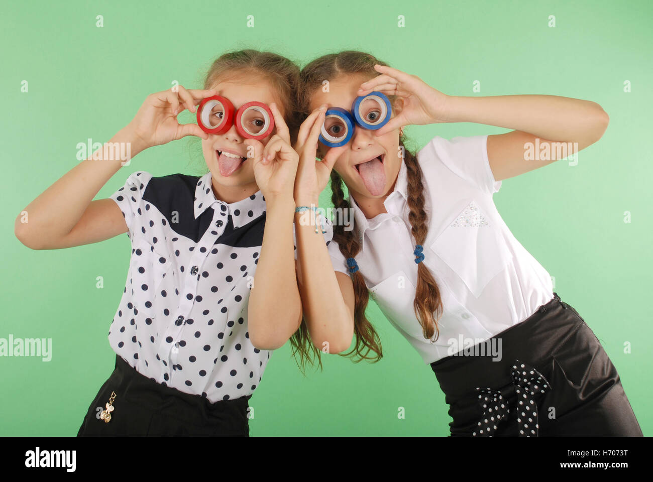 Due belle scuola ragazza con due nastri isolanti sugli occhi per guardare radiante su verde Foto Stock