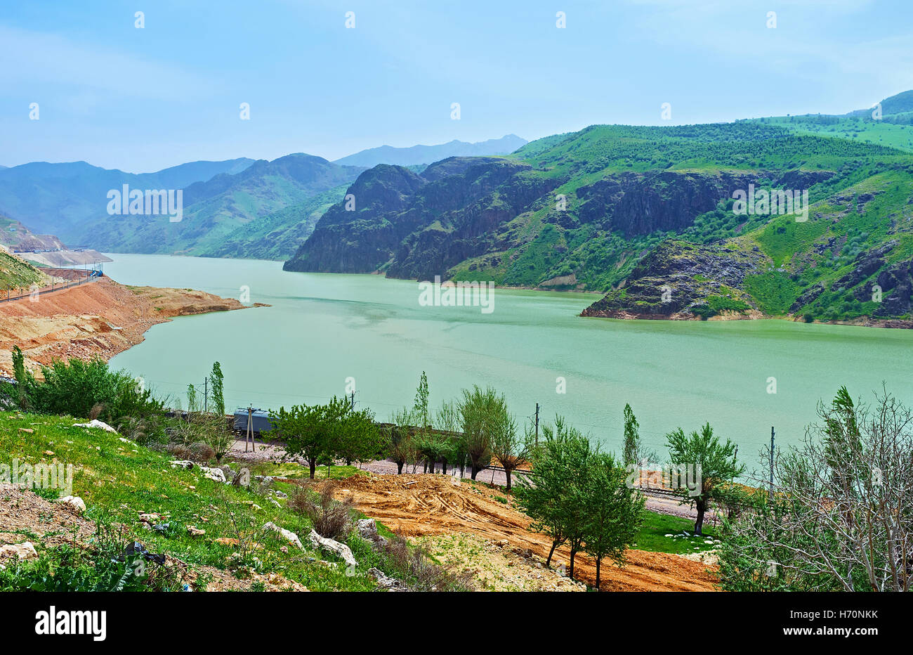 Le acque verdi del serbatoio Achangaran con il Qurama montagne sullo sfondo, Uzbekistan. Foto Stock