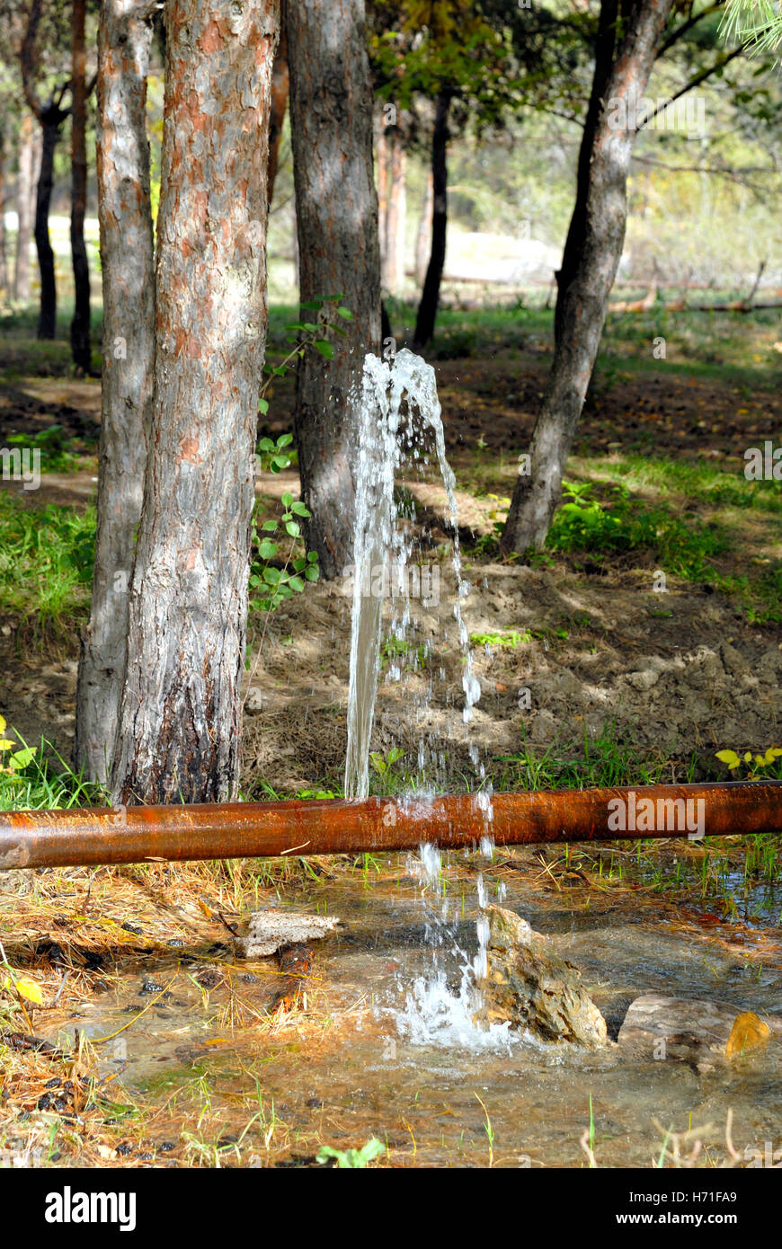 La perdita di acqua da una cricca in un vecchio tubo arrugginito Foto Stock
