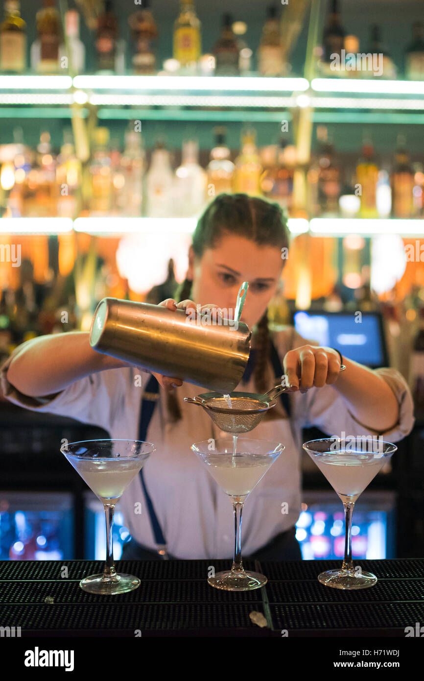 Una donna fa dei cocktail al bar. Foto Stock