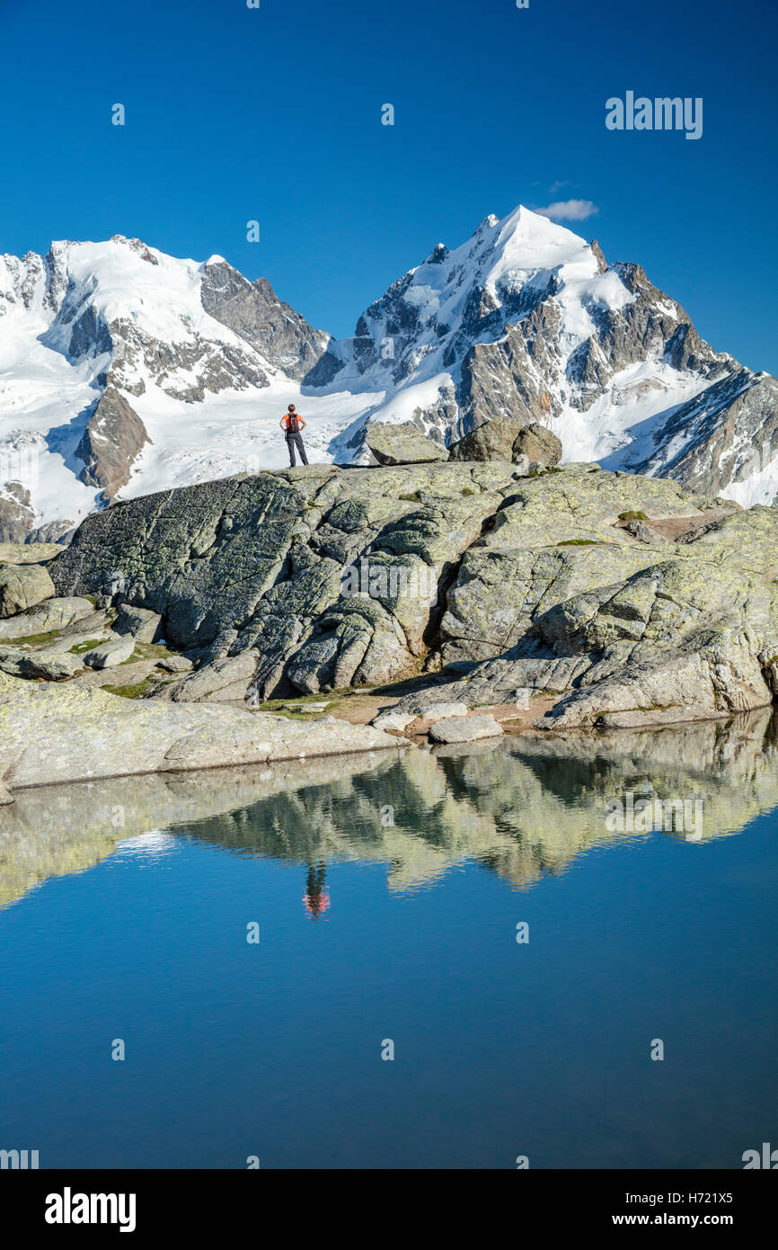 La riflessione di un escursionista sotto il Piz Bernina e Piz Rosbeg. Fuorcla Surlej, Silvaplana, Berniner Alpi, Grigioni, Svizzera. Foto Stock
