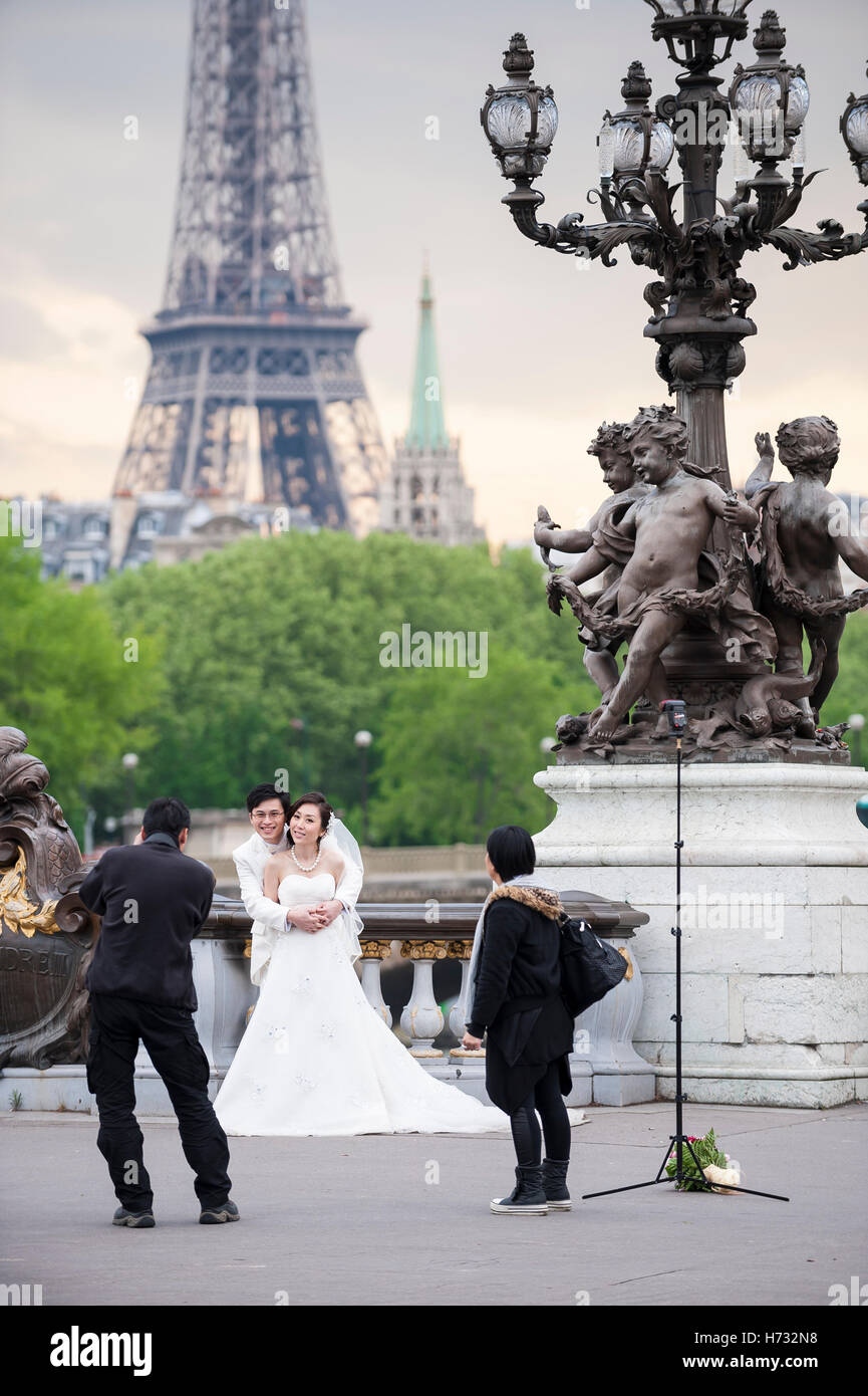 Parigi - 19 Maggio 2013: Asian sposa e lo sposo pone per le fotografie sul Pont ponte Alexandre III con una vista della Torre Eiffel. Foto Stock