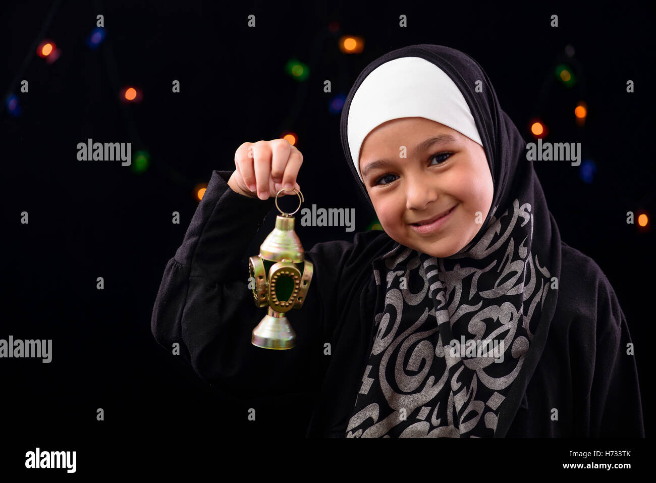 Felice ragazzina musulmana che celebra con il Ramadan Lanterna sulla notte sfocati sullo sfondo delle luci Foto Stock