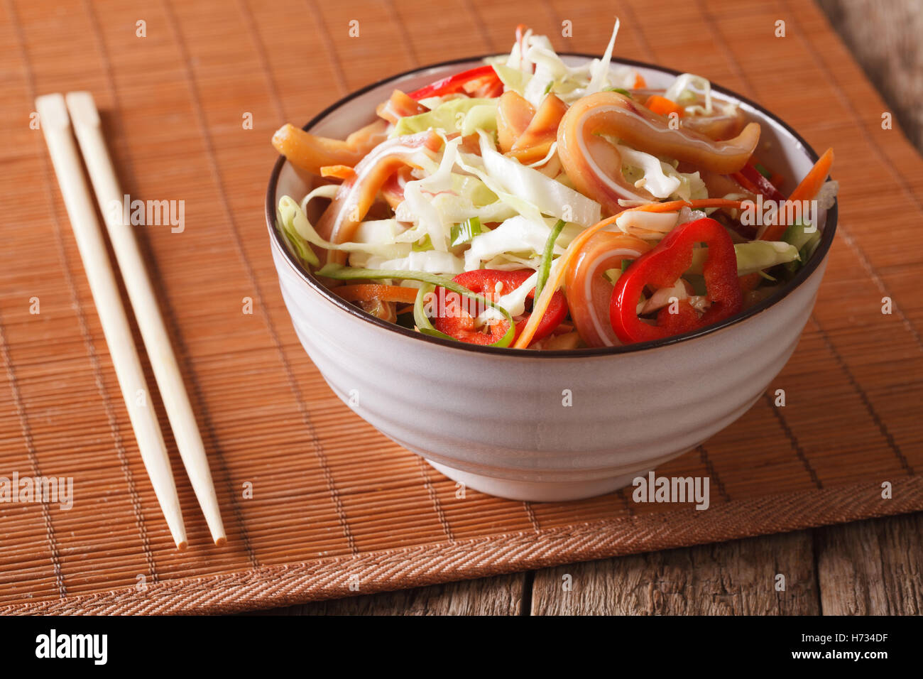 Cibo asiatico: delle orecchie di maiale con insalata di verdure fresche di close-up in una ciotola sul tavolo orizzontale. Foto Stock