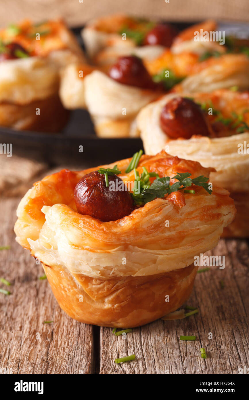 Muffin di pasta sfoglia con salsiccia e formaggio vicino sul tavolo. In verticale Foto Stock