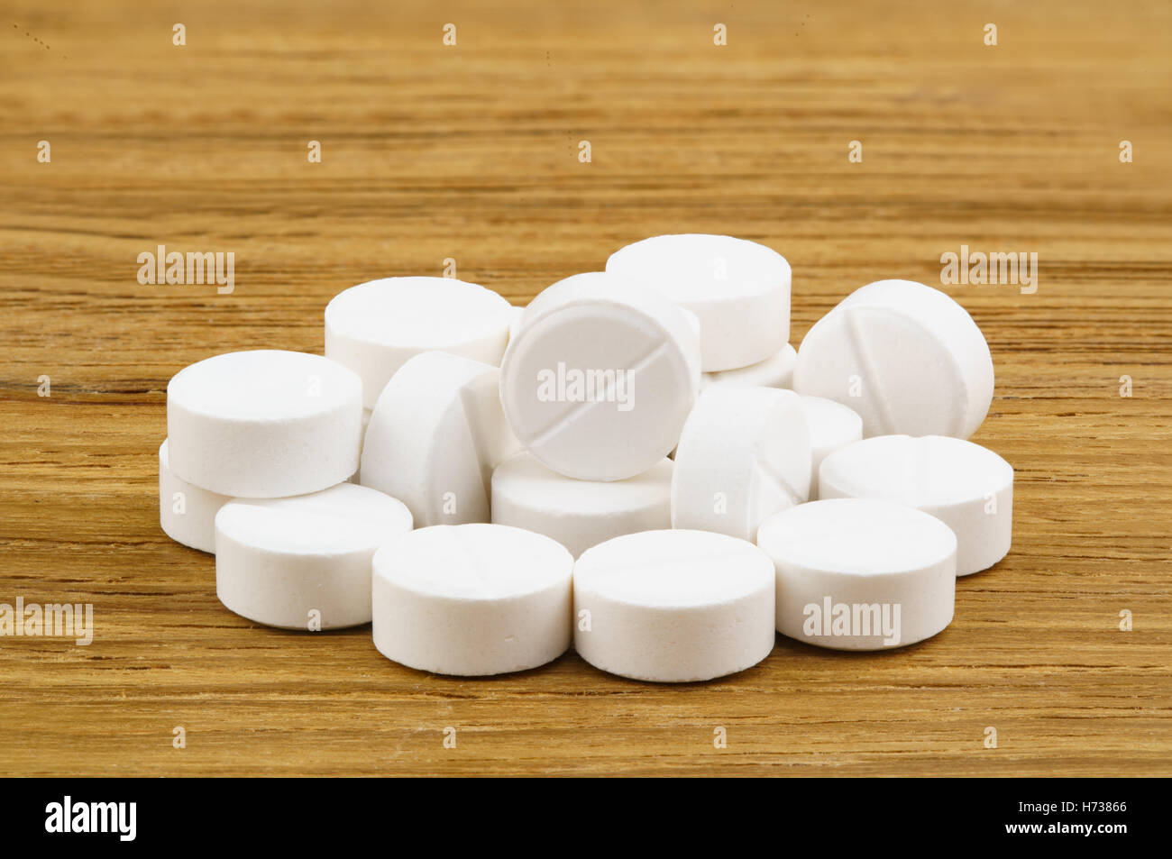 Pila di bianco pillole di medicina su uno sfondo di legno Foto Stock