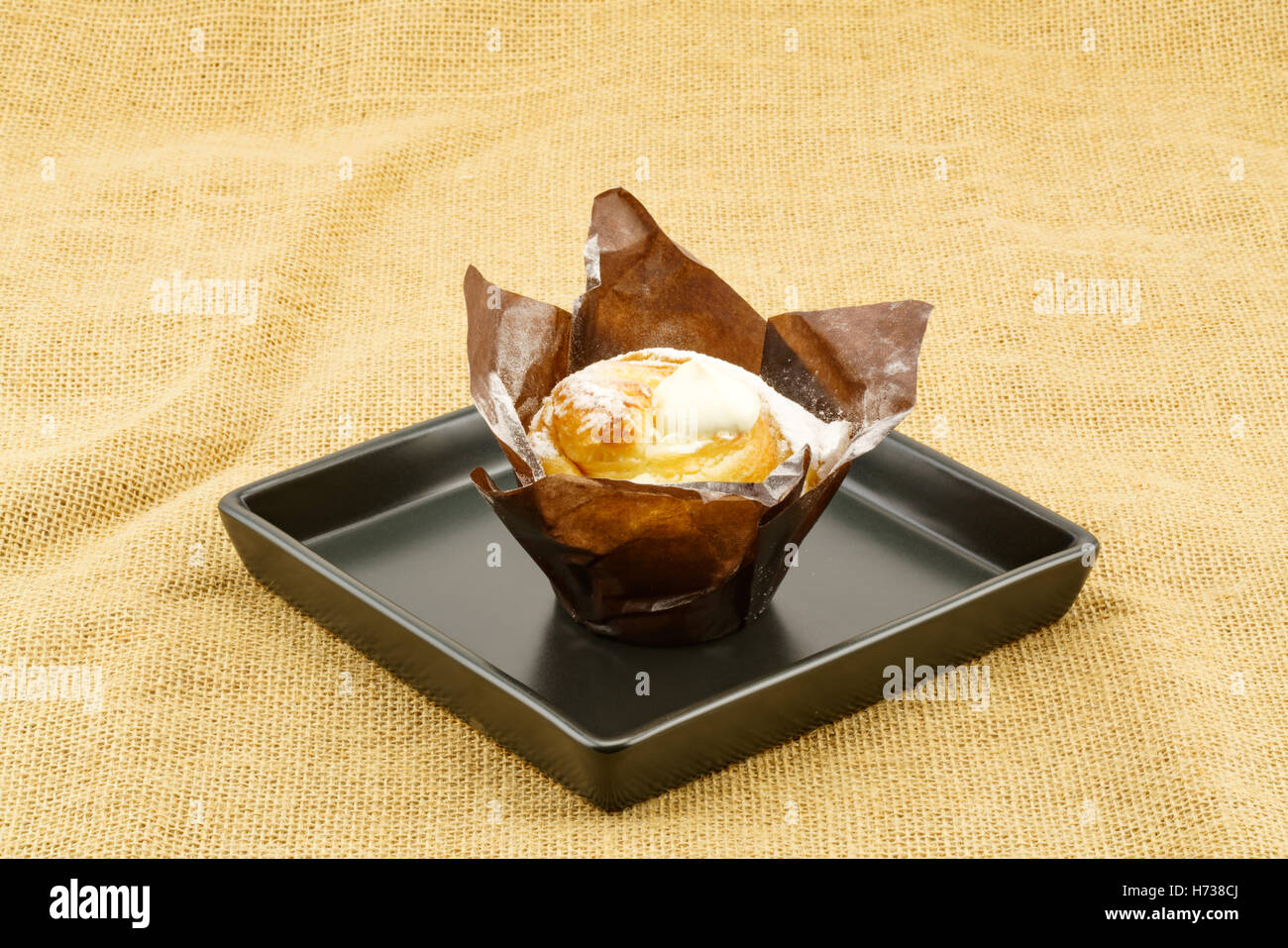 Cruffin creme brulee in piastra nera posto su un letto di sacco Foto Stock