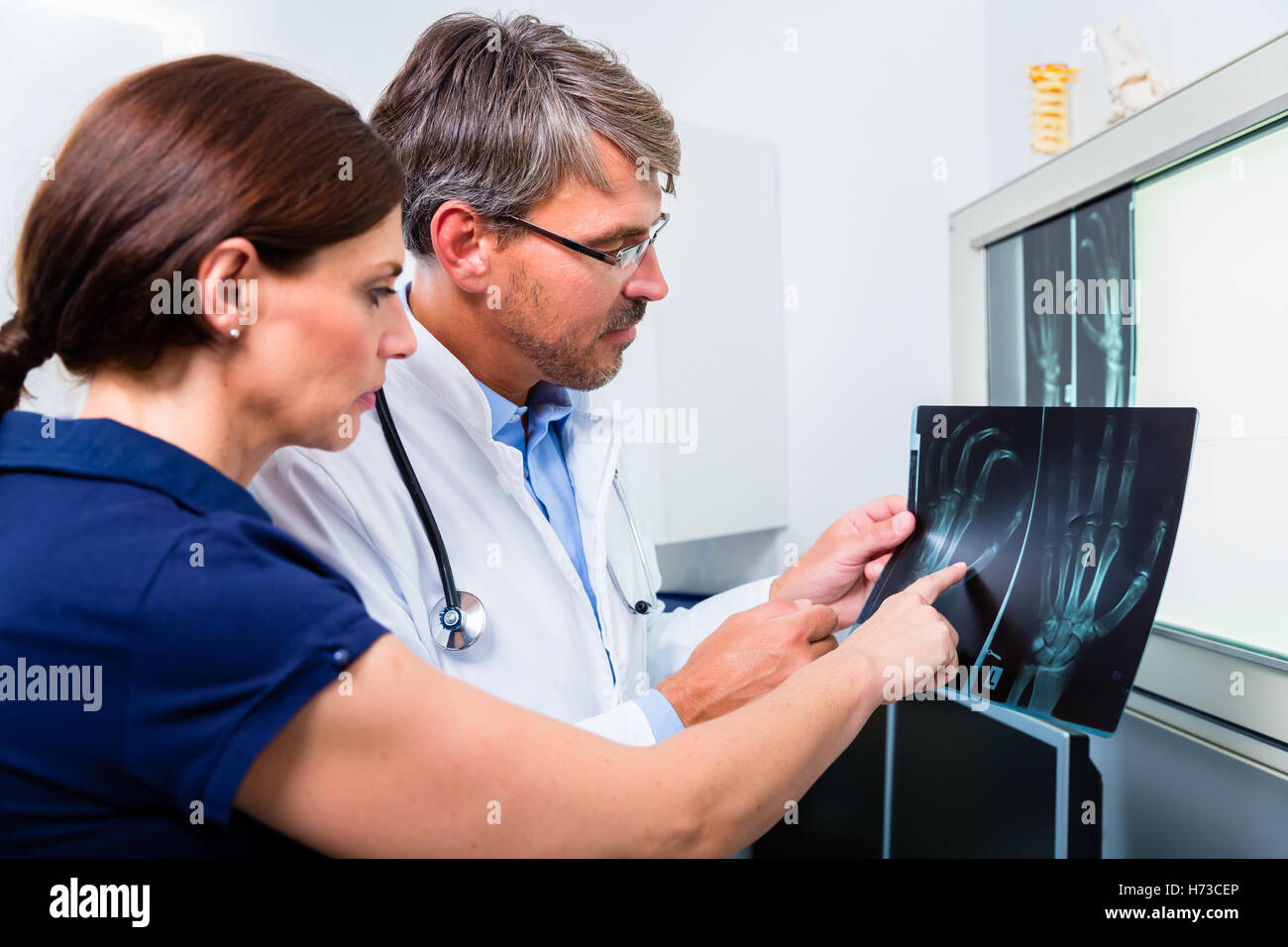 Medico con immagine a raggi x della mano del paziente Foto Stock