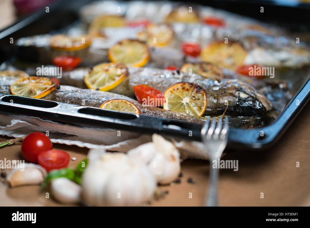 Trota di delizioso pesce al forno con limone, pomodori e spezie Foto Stock