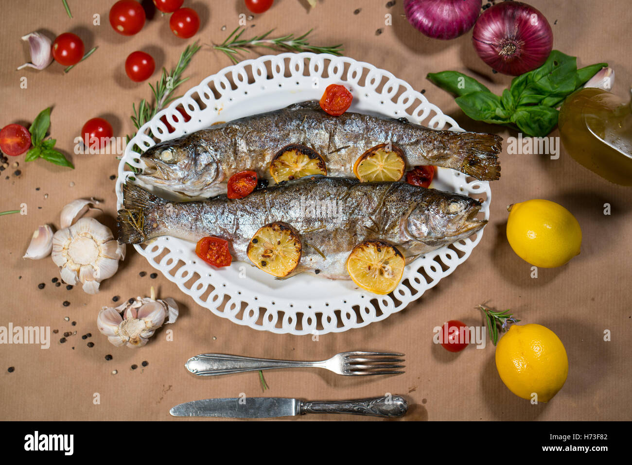 Trota di delizioso pesce al forno con limone, pomodori e spezie Foto Stock