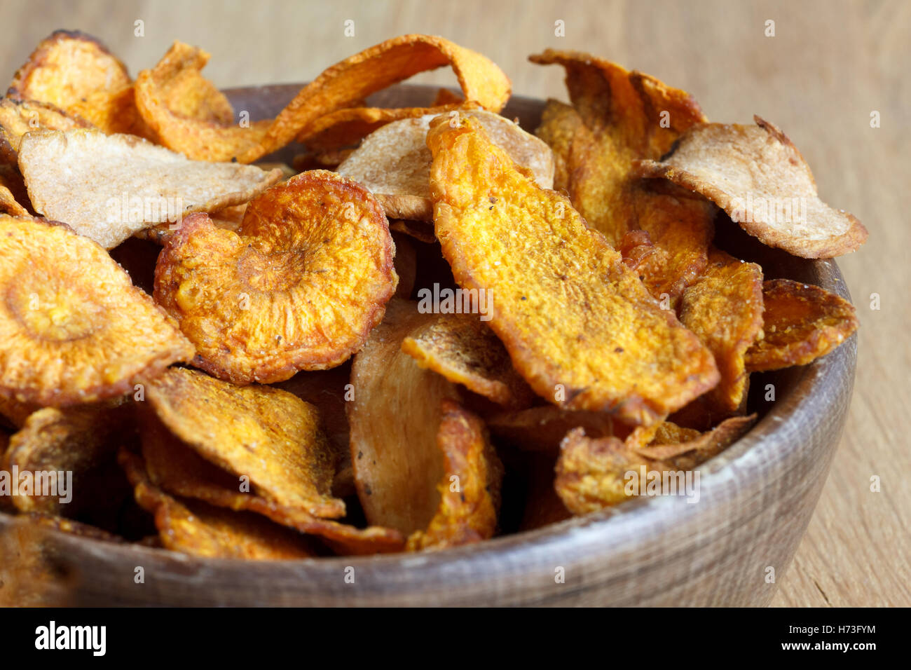 Dettaglio della frittura di carota e pastinaca trucioli in legno rustico ciotola. Foto Stock