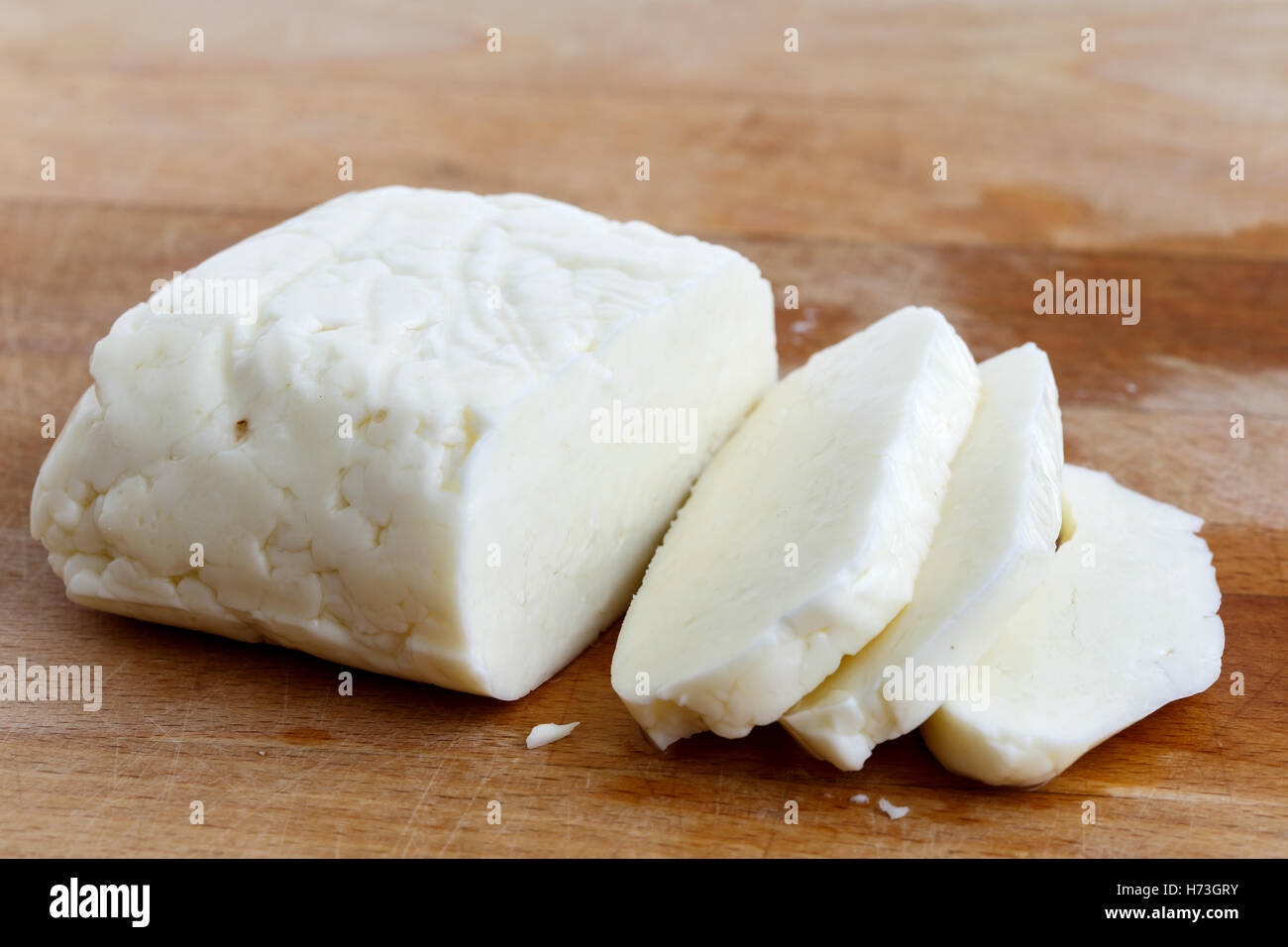 Tagliate a fette il formaggio halloumi sulla tavola di legno in prospettiva. Foto Stock