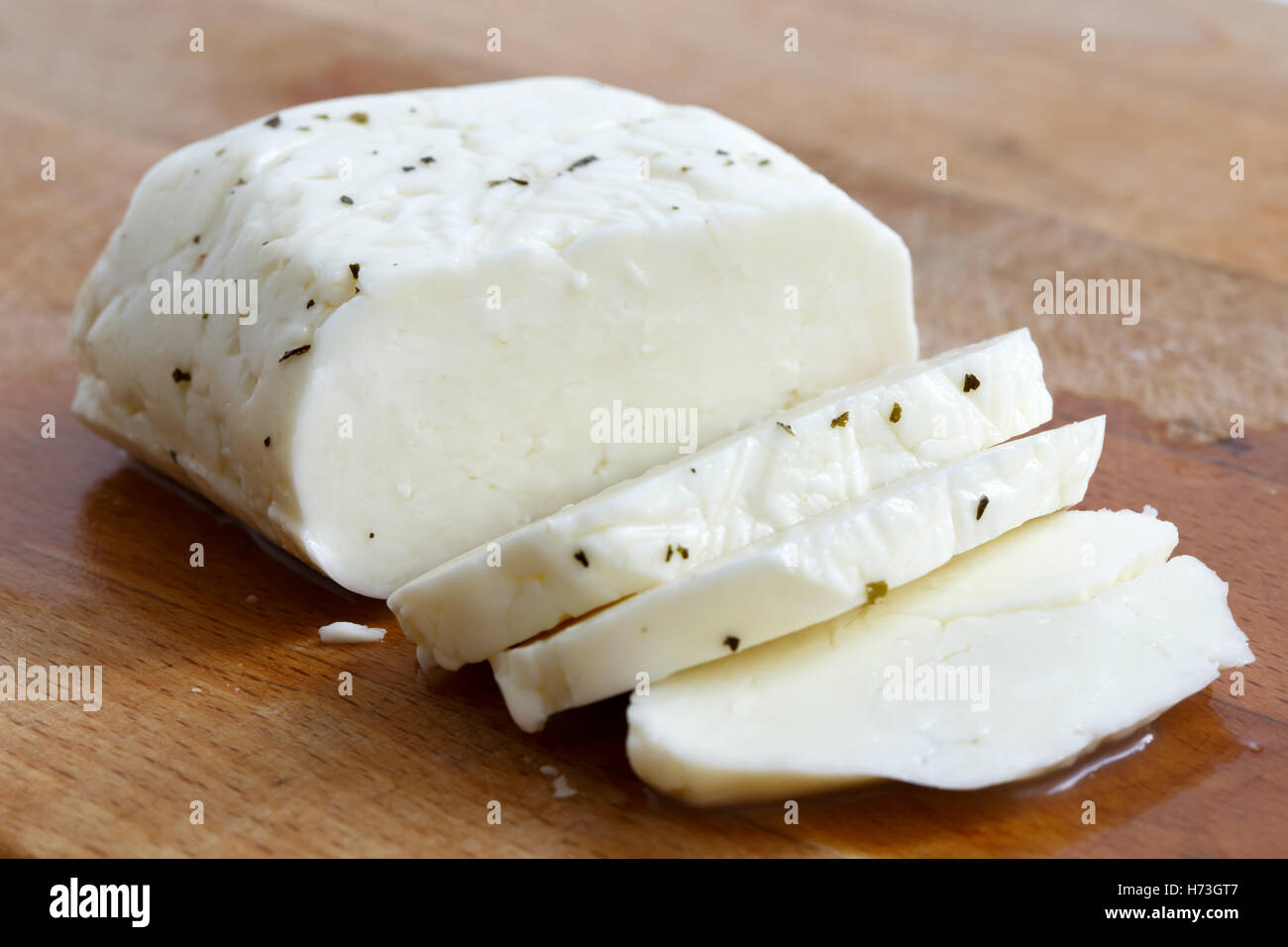 Tagliate a fette il formaggio halloumi con menta su tavola di legno in prospettiva. Foto Stock