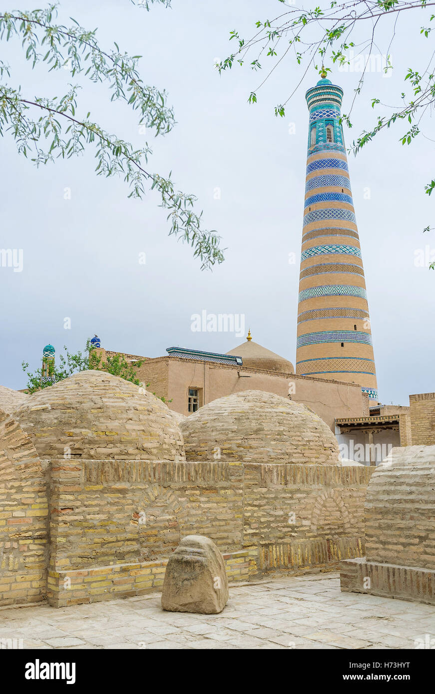 La vista sull'Islam Khoja Minaret dietro il mattone medievale mausolei, Khiva, Uzbekistan. Foto Stock