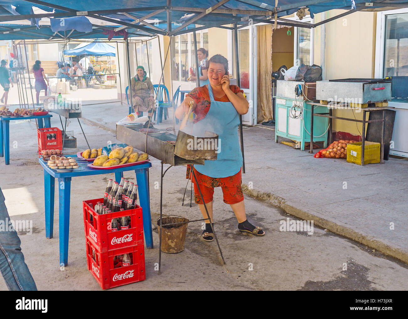 Il cuoco presso il mercato in stallo prepara torte e shish kebab sul grill Foto Stock