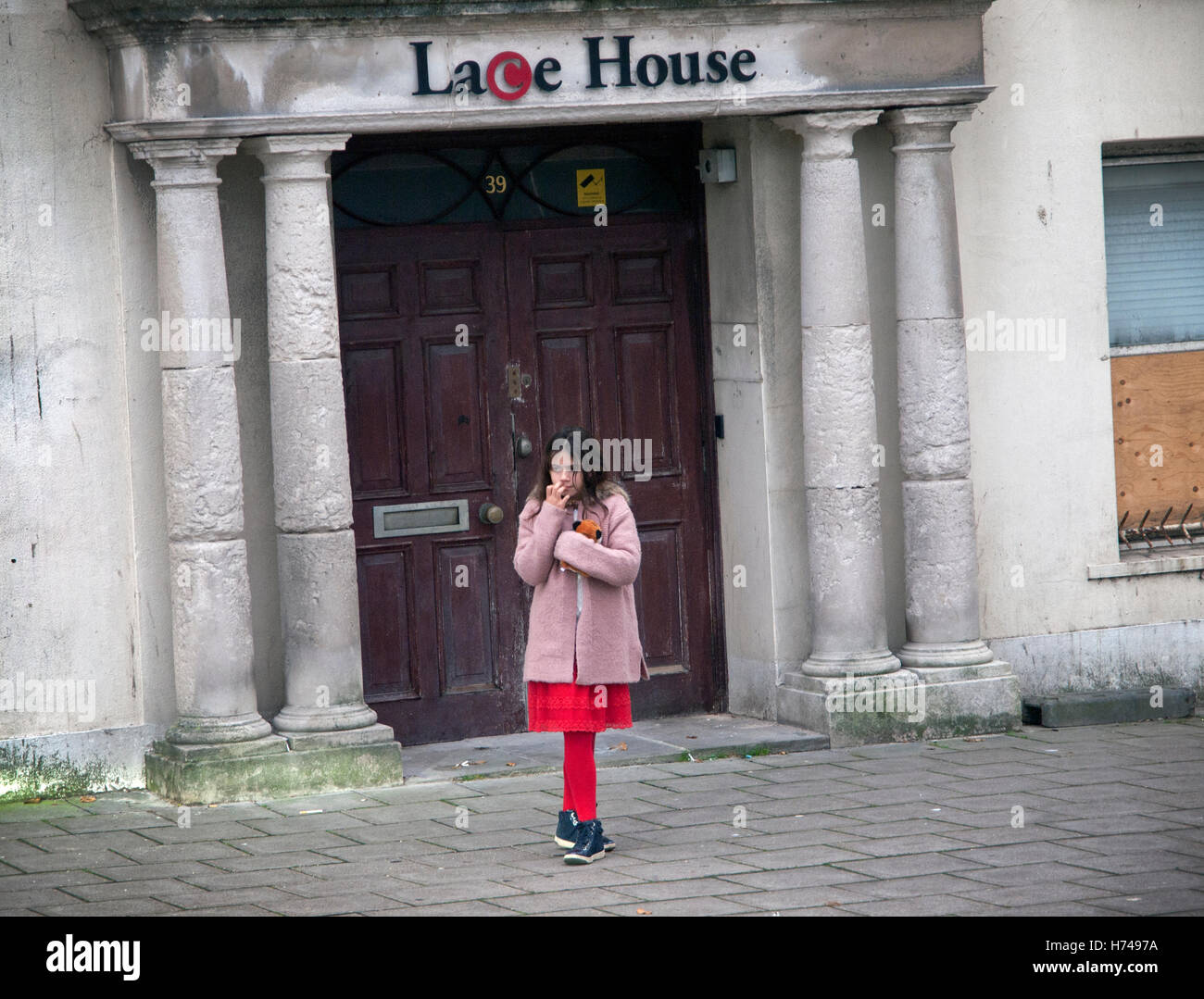 Una ragazza in rosso collant sorge fuori casa in pizzo in Brighton Foto Stock