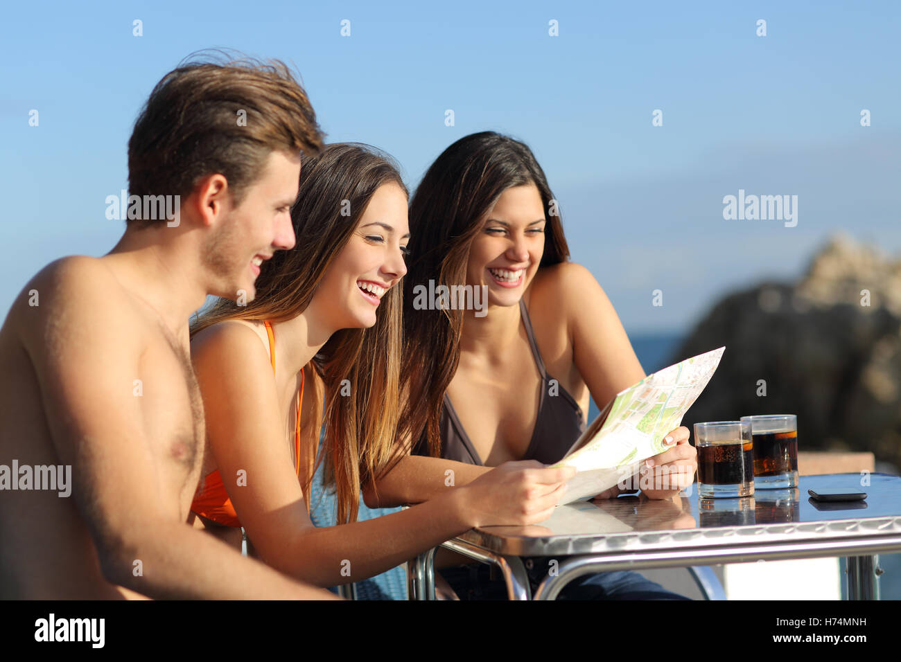 Amici in vacanza la consultazione di una guida in un hotel terrazza Foto Stock