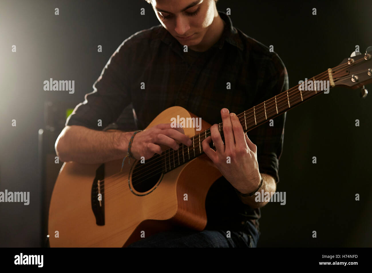 Uomo che utilizza la tecnica di maschiatura sulla chitarra acustica Foto Stock