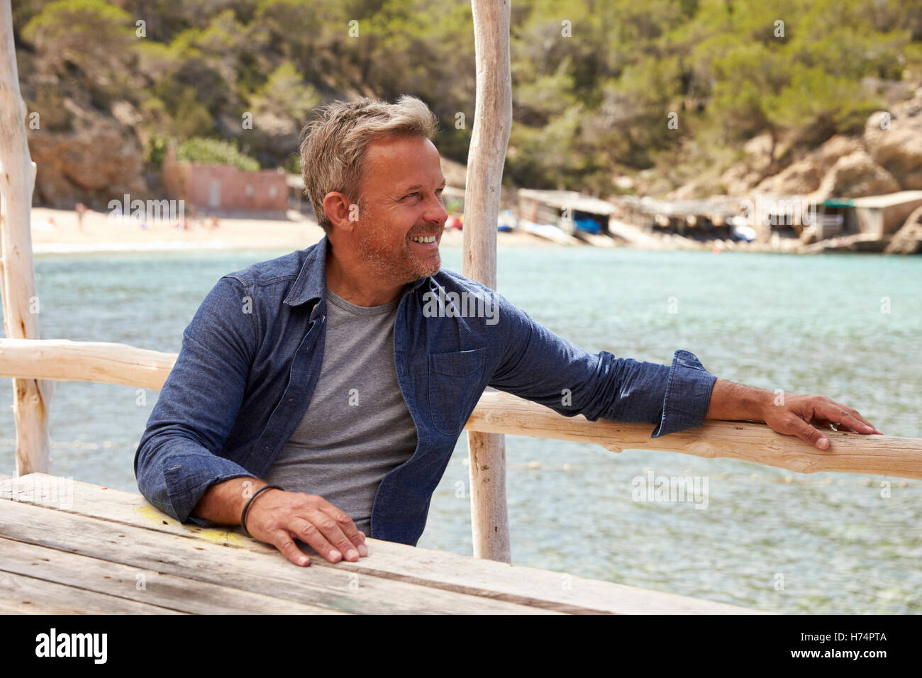 Persone di mezza età uomo caucasico seduti ad un tavolo in riva al mare Foto Stock