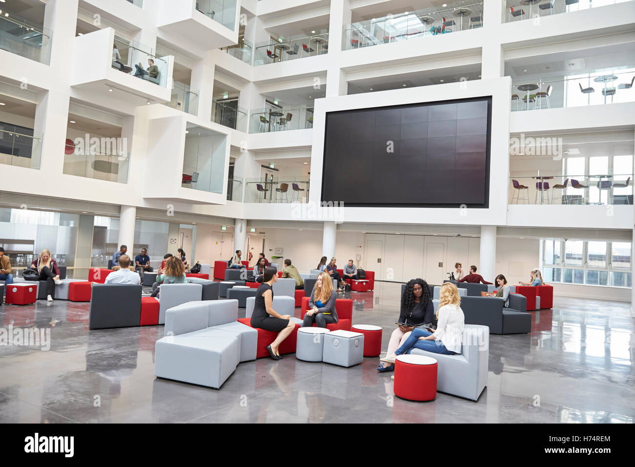 Gli studenti riuniti nella parte anteriore dello schermo in atrium presso l' università Foto Stock