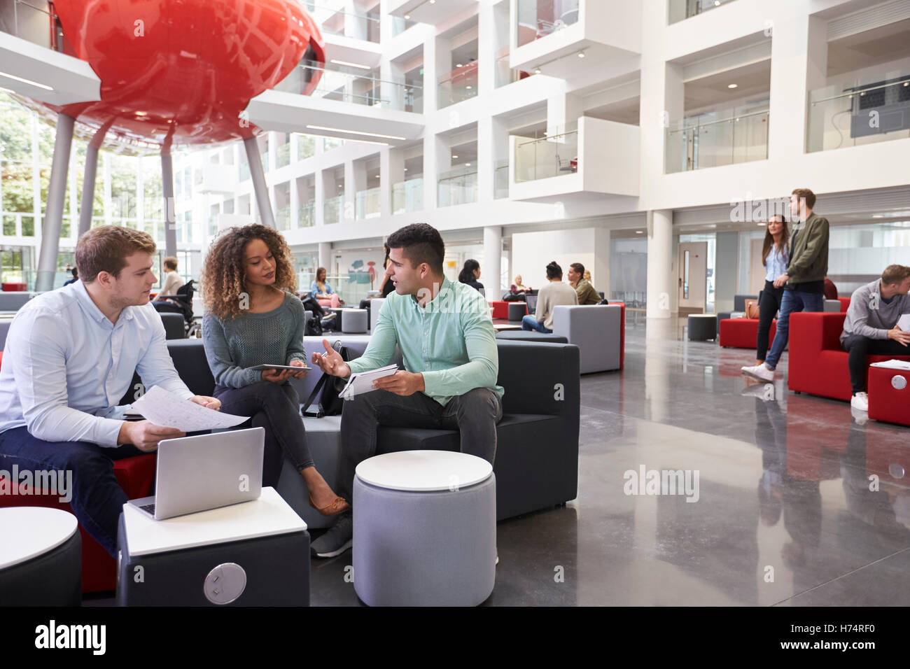 Agli studenti universitari atrium, tre in primo piano vicino fino Foto Stock