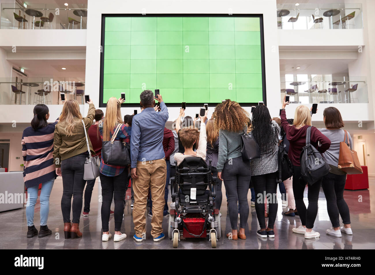 Gli studenti fotografia schermo con telefoni, vista posteriore a piena lunghezza Foto Stock